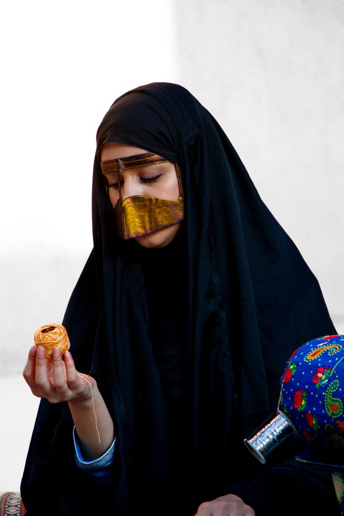 A woman in traditional Emirati attire holding a cultural artifact in Dubai, UAE.