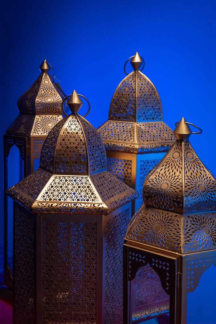 Artistic display of ornate Arabic lanterns with intricate designs on a vivid blue backdrop, symbolizing cultural festivity.