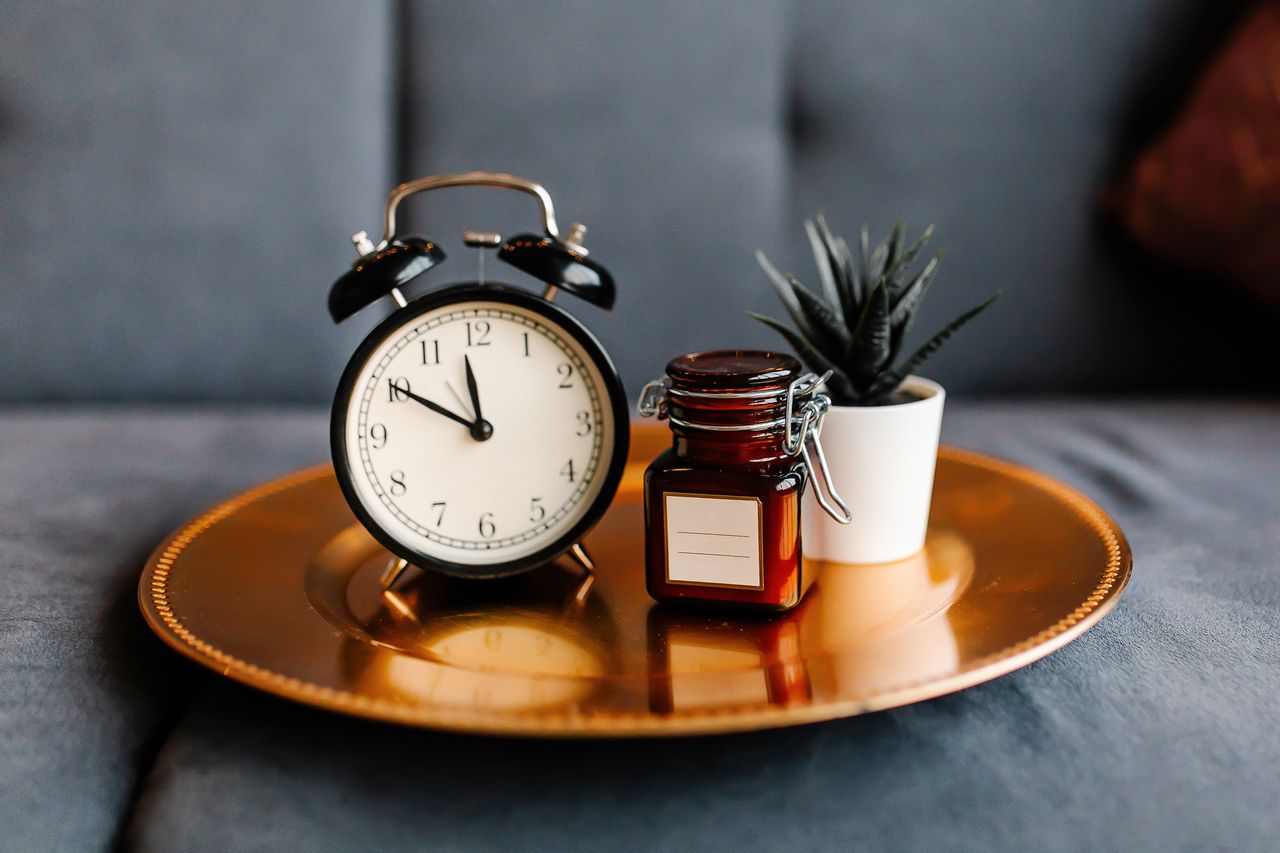 Contact Aesthetic arrangement of a clock and jar on a golden tray with a potted plant.