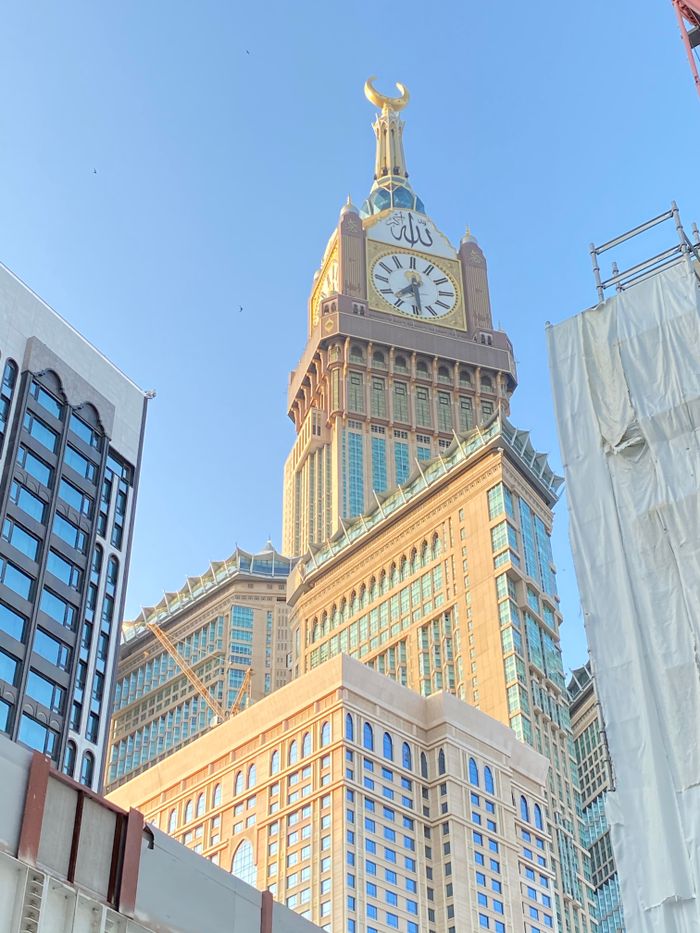 The Abraj Al Bait Towers in Makkah, featuring a prominent clock tower against a clear blue sky.